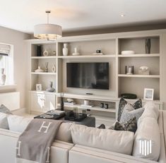 a living room filled with white furniture and a flat screen tv mounted on a wall