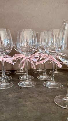 several wine glasses with pink bows are lined up in a row on a counter top