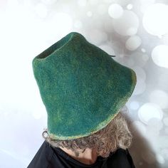 This Tall Bucket Hat with Felted Leaf is an understated hat that is easy to wear. It's a kind of fly-under-the-radar kind of hat. The hand-felted leaf decoration adds a bit of unique pizazz. If you like, you can turn the brim snazzily upwards. COLOUR: • The colours of this hat are a heathered blue-green with a yellowish undertone. Along the brim edge, it's a lighter yellow-green. The underside of the brim is a celadon green with contrasting decorations of yellow and spring green circles. SHAPE: Green Felt Hat For Winter, Handmade Wool Felt Hat With Wide Brim, Handmade Felt Hat With Short Brim, Curved Brim Felt Hat, Green Brimmed Felt Hat, Curved Brim Felt Hat, One Size Fits Most, Green Felt Brimmed Hat, Handmade Fur Felt Hat With Curved Brim, Handmade Green Felt Hat With Curved Brim