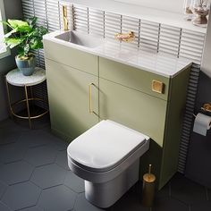 a bathroom with a toilet, sink and mirror next to a plant in the corner