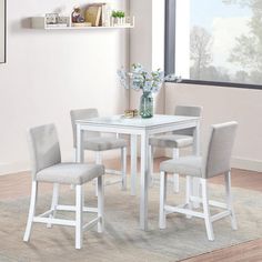 a white table and chairs in a room with a rug on the floor next to it