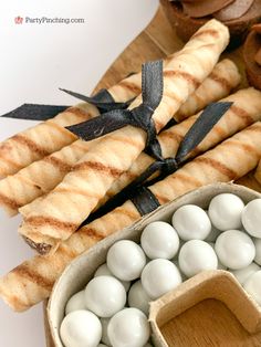 some food is laying out on a wooden cutting board next to bread sticks and marshmallows