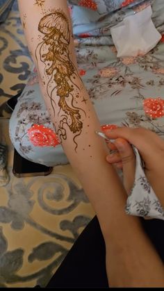 a woman is getting her arm painted with hendix and gold leaf designs on it