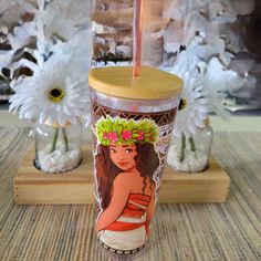 a cup with a straw in it sitting on a table next to flowers and vases