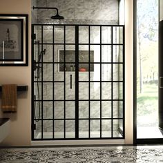 a bathroom with a glass shower door and tile flooring, along with framed pictures on the wall