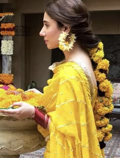 a woman in a yellow dress holding a plate with flowers around her neck and head