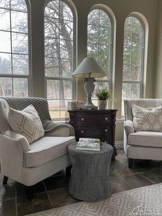 a living room with two couches and chairs in front of three large arched windows