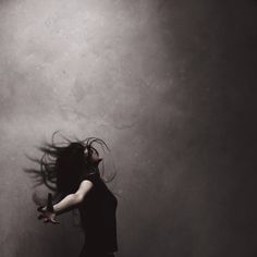 a woman with her hair flying in the air while she is holding a skateboard