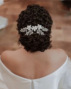 a woman with curly hair wearing a white dress and a bridal headpiece in her hair