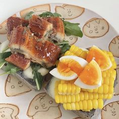 a plate with some food on it including eggs, corn and bacon next to other foods