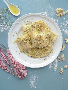 a white plate topped with ravioli and pistachio