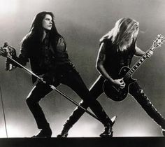 two women in black outfits with guitars and microphones, one is holding a guitar