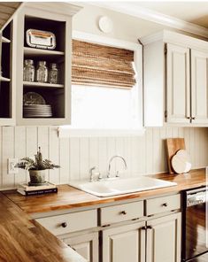 a kitchen with white cabinets and wooden counter tops, along with an open shelf above the sink