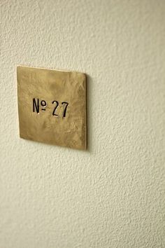 a gold square with the number 27 on it is mounted to a white painted wall