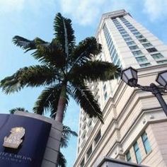 a tall palm tree next to a hotel sign and lamp post in front of a building