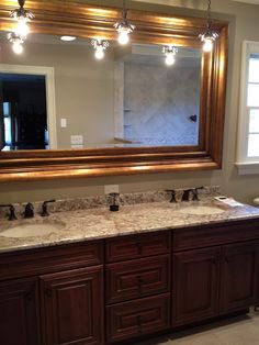 a bathroom vanity with two sinks and a large mirror over the sink in front of it