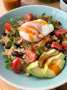 a blue bowl filled with rice, avocado, tomatoes and an egg on top