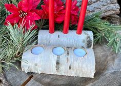 some red candles are sitting on a piece of wood