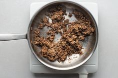 a frying pan filled with food on top of a white stove burner next to a spatula