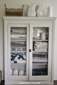 a white cabinet filled with folded towels and dishes