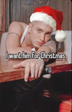 a man wearing a santa hat sitting at a table with his hand on the desk