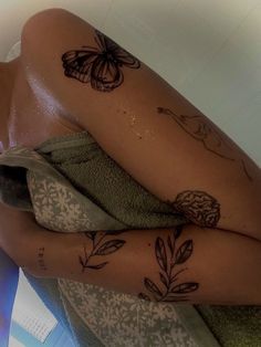 a woman with tattoos on her legs sitting in a bath room next to a towel