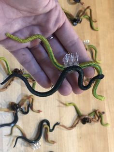 a hand holding a string wrapped snake in it's left hand and several other snakes on the floor