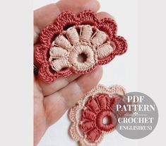 two crocheted flowers are being held in the palm of someone's hand