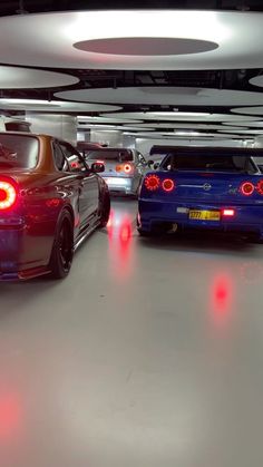 three cars parked in a parking garage with red lights on the taillights and one blue car