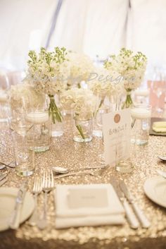 the table is set with silverware and white flowers