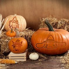 two pumpkins with faces carved into them sitting on hay next to some corn stalks