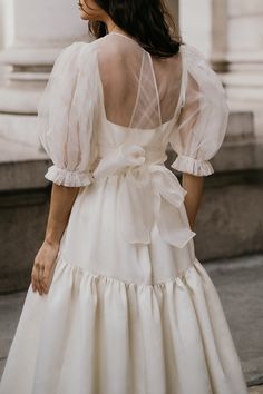 the back of a woman's dress with sheer sleeves and a bow at the waist