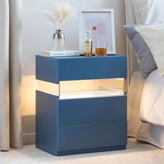 a blue night stand with two drawers and a white pillow on the bed next to it