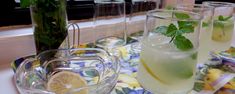 four glasses filled with lemonade and mint on a tray next to a window sill