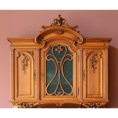 an ornate wooden cabinet against a pink wall