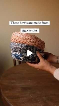 a person holding three hats on top of a wooden table with text above it that reads, these bowls are made from egg cartons