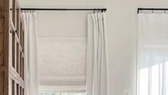 two white curtains hanging from the side of a window