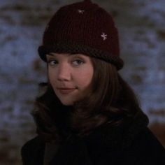 a woman wearing a knitted hat with stars on the front and side, looking at the camera