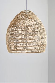 a rattan light fixture hanging from a ceiling in a room with white walls and flooring