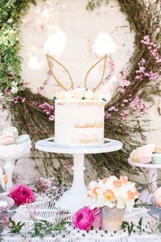 a white cake sitting on top of a table next to other desserts and flowers