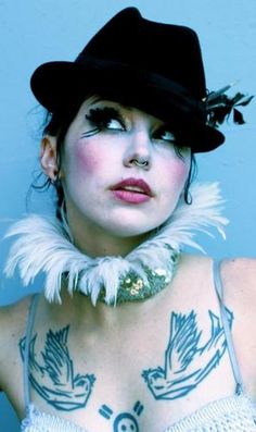 a woman with tattoos on her chest wearing a hat