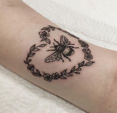 a black and white photo of a bee in a circle with leaves on it's arm