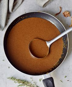 there is a spoon in a pan with some food on the table next to it