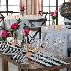 the table is set with wine glasses, candles and flowers in vases on it