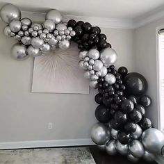 a bunch of black and silver balloons hanging from the ceiling