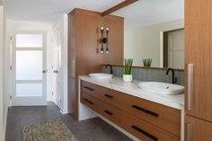 a bathroom with double sinks and wooden cabinets