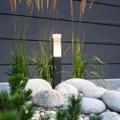 a light that is on in the middle of some rocks and grass next to a building