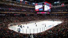 an ice hockey game is being played in a large arena with people watching from the stands