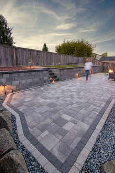 a person walking across a stone patio near some rocks