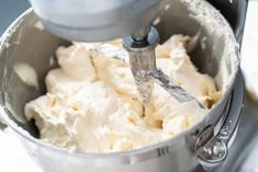 a mixer filled with cream sitting on top of a counter